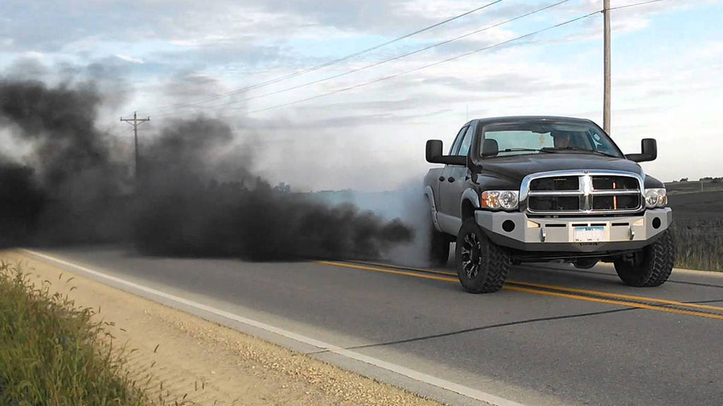 CUMMINS license plate on Dodge Ram pickup with heavy black smoke, rolling coal